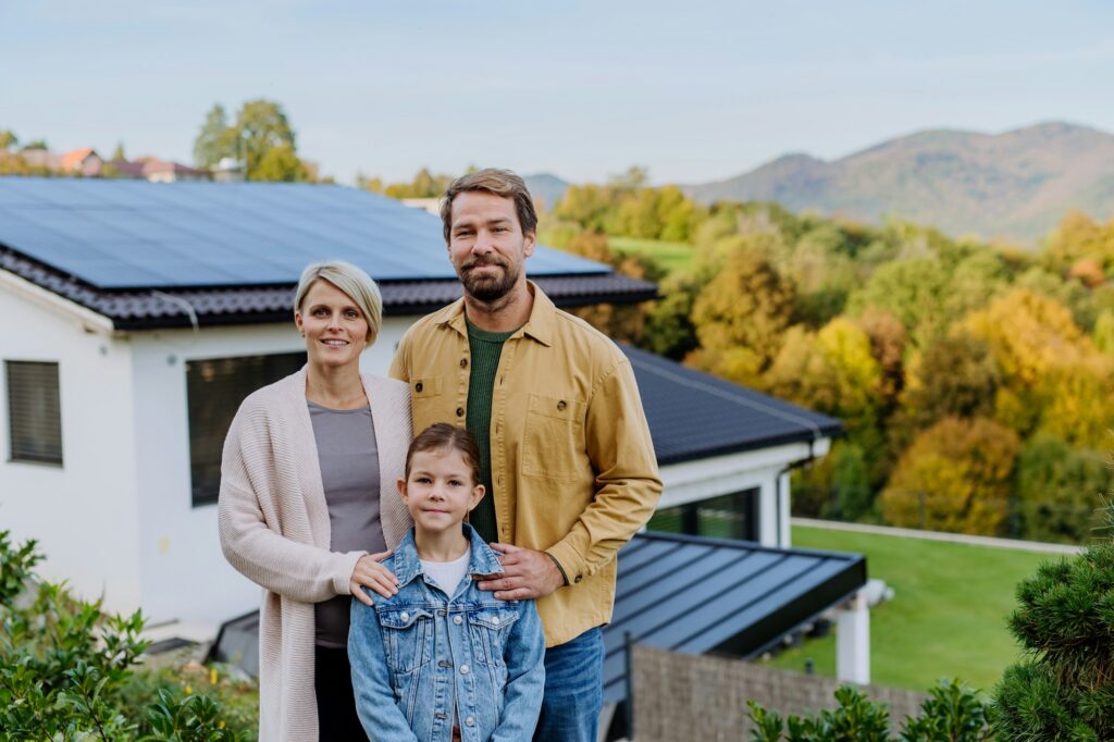 Happy family near their house with solar panels. Alternative energy, saving resources and