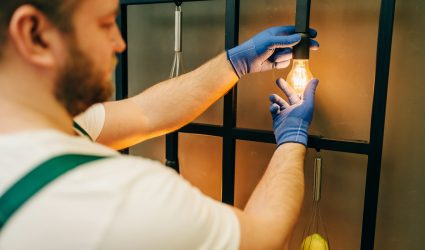 Electrician changes the light bulb, handyman